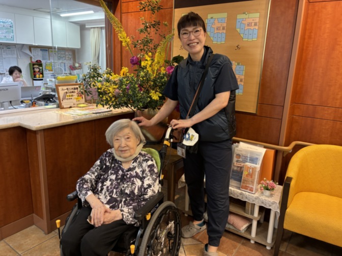 スタッフが入居者と花を前に笑顔でポーズ。ロビーの受付エリア