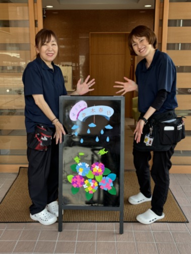 スタッフ2名が制作した季節の装飾作品を前に笑顔で記念撮影。