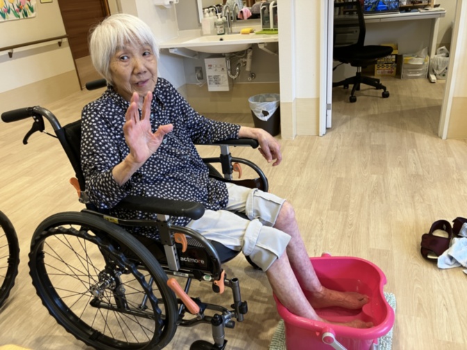 車いすに乗る高齢女性の日常風景。施設内での生活の様子を示す写真。