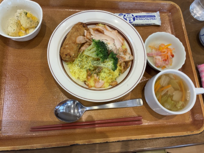 介護施設の食事風景。木製トレーに盛り付けられた親子丼と複数の小鉢。