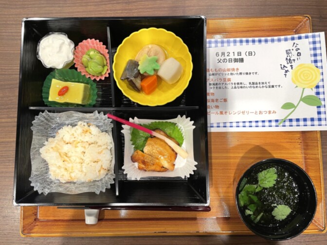 介護施設の栄養バランスが取れた食事。黒い四角弁当箱に複数品が盛られている。