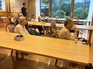 複数の高齢者入居者が木製テーブルで卓上活動に参加している様子