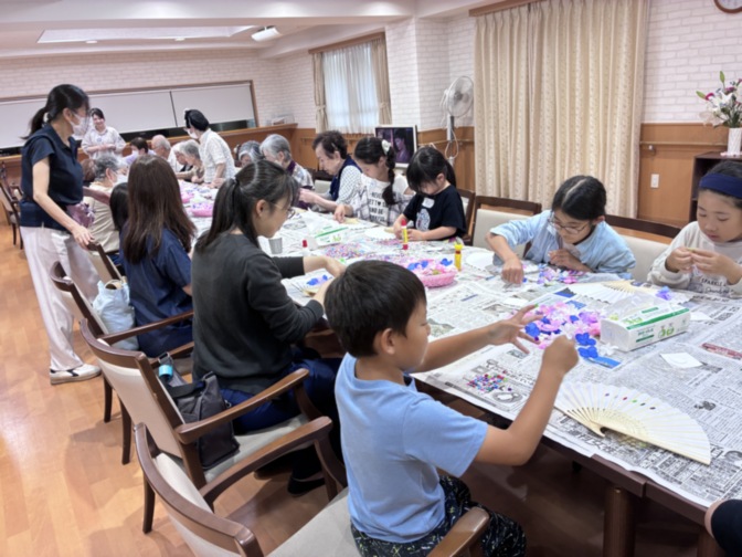 介護施設での入居者向けレクリエーション。スタッフが見守る中、複数の高齢者が絵画活動に取り組んでいる。
