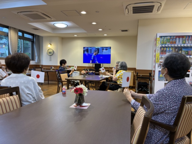 入居者がテレビを観ながら過ごす共用ラウンジ。テーブルと椅子が配置されている。