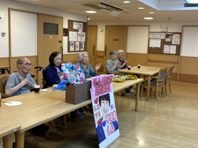 介護施設の共用スペースで入居者たちがイベントに参加している風景