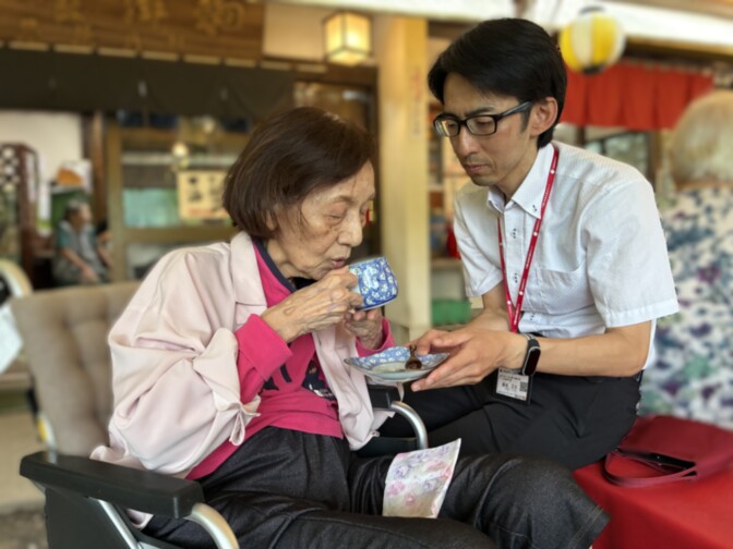 職員と入居者が手工芸活動で陶芸作品を一緒に楽しむ様子