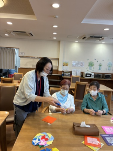 スタッフが入居者と一緒にレクリエーション活動を行っている様子。テーブルで工作や手工芸を楽しむ風景。