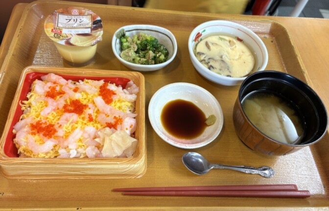 介護施設の食事風景。木製トレイに盛られた海老チャーハン、副菜、汁物が提供されている。