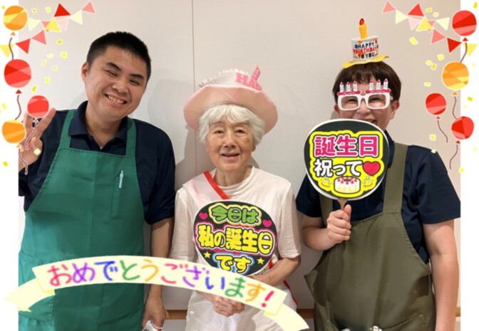 スタッフと入居者が誕生日を祝うレクリエーション風景。装飾とプロップスで楽しい雰囲気。